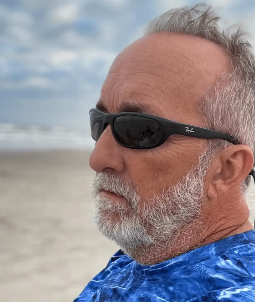 Headshot of author Jay Thompson, sitting on a beach